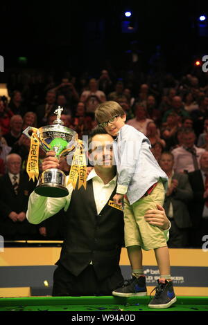 Ronnie OSullivan pone con il trofeo e di suo figlio dopo aver vinto contro Barry Hawkins nella partita finale del World Snooker Championships presso il Cr Foto Stock