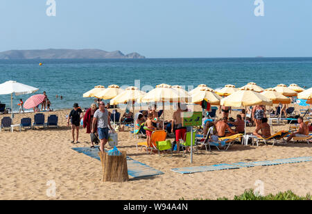 Iraklion, Creta, Grecia. Giugno 2019. Acapulco Beach si trova vicino all'aeroporto Iraklion. I turisti a prendere il sole. Dia isola disabitata in background. Foto Stock