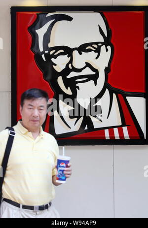 --FILE--A passeggiate a piedi passato un annuncio pubblicitario per KFC un fast food ristoranti di Yum brand in Cina a Shanghai, 13 agosto 2013. La Cina è stata una bona Foto Stock