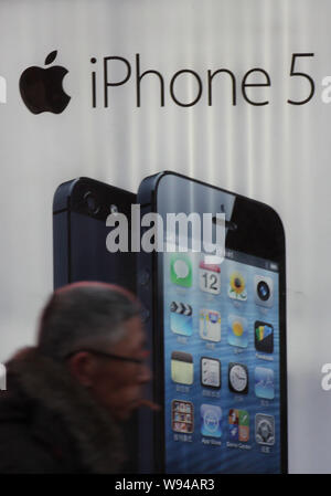 --FILE -- un anziano uomo cammina passato un annuncio pubblicitario di Apple iPhone 5 smartphone in città Qindao, est Chinas provincia di Shandong, 31 dicembre 2012. Apple Foto Stock