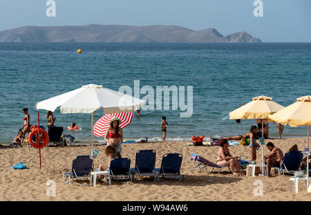 Iraklion, Creta, Grecia. Giugno 2019. Acapulco Beach si trova vicino all'aeroporto Iraklion. I turisti a prendere il sole. Dia isola disabitata in background. Foto Stock