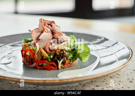 Messa a fuoco selettiva di appetitose insalate cotte nel ristorante per la cena. Gustoso prosciutto con verde, pepe, funghi, cipolla e senape su piastra in cafe. Concetto di cibo, pasto e cucina. Foto Stock