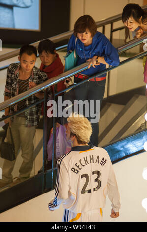 --FILE--acquirenti cinesi guardare una cera figura del calcio inglese superstar David Beckham realizzato da Madame Tussauds presso un centro commerciale per lo shopping a Chongqing, Chi Foto Stock