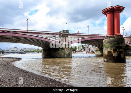 Blackfriars road bridge dalla riva sud del fiume Tamigi a bassa marea, pilastri del ponte vecchio sulla destra, London, Regno Unito Foto Stock