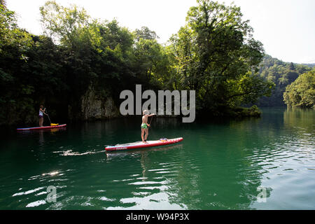 Madre e figlio divertendosi in stand up paddle sul bellissimo fiume Idrijca a Most na Soci, Slovenia Foto Stock