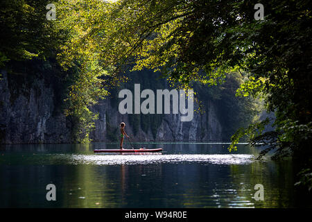 Ragazzo giovane divertendosi in stand up paddle sul fiume Idrijca a Most na Soci, Slovenia Foto Stock