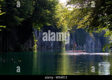 Ragazzo giovane divertendosi in stand up paddle sul fiume Idrijca a Most na Soci, Slovenia Foto Stock