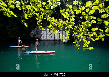 Madre e figlio divertendosi in stand up paddle sul bellissimo fiume Idrijca a Most na Soci, Slovenia Foto Stock