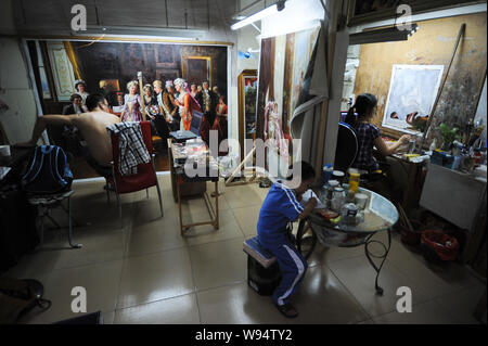 Un giovane ragazzo cinese fa il suo dovere come i suoi genitori sono la verniciatura nel loro studio di casa nel Villaggio della Pittura ad Olio Dafen, città di Shenzhen, sud Chinas Guan Foto Stock