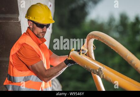 Lavoratore caucasici con alta tensione tubo di plastica. Metropolitana linea elettrica dell'installazione. Industria edile. Foto Stock