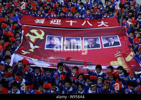 Giovani studenti cinesi wave bandiere nazionali e ne spiegherà un banner con le foto di quattro generazioni di dirigenti cinesi (da sinistra) Mao Zedong, Deng Xiaopin Foto Stock