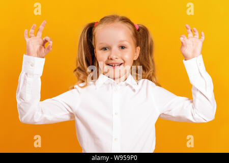 Carino sorridente bambina mostra segno ok con due mani. Il concetto di successo e l'istruzione. Foto Stock