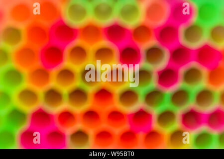 Sfocare lo sfondo di variopinti cocktail di plastica tubi. Backgdrop di colore giallo brillante, rosso, rosa e verde colori al neon. Abstract sfondo colorato. Foto Stock