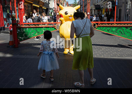 Pokemon Pikatchu che la gente paga per avere le loro foto scattata con in Chinatown, Londra, Inghilterra, Regno Unito. Pikachu sono una specie di Pokemon, creature fictional che compaiono in un assortimento di video giochi, animate e spettacoli televisivi e i film, i giochi di carte collezionabili, e fumetti e concesso in licenza da The Pokémon Company, un'azienda giapponese. Foto Stock