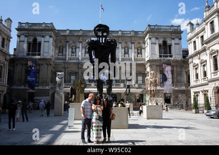 Le persone al di fuori dell'entrata alla Royal Academy per l'estate mostra a Londra, Regno Unito. L'estate mostra è aperta la mostra d'arte che si tengono annualmente dalla Royal Academy di Burlington House Piccadilly nel centro di Londra, Inghilterra, durante i mesi di giugno, luglio e agosto. La mostra include dipinti, stampe, disegni, sculture, modelli architettonici e modelli, ed è il più grande e più popolare esposizione aperta nel Regno Unito. È anche la più lunga in modo continuo in scena per le esposizioni di arte contemporanea in tutto il mondo. Foto Stock