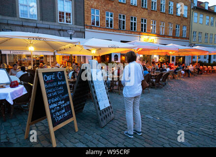Il ristorante di Copenaghen; Donna che guarda il menu su una notte estiva, Cafe G ristorante, Gråbrødretorv, Quartiere Latino, Copenhagen, Danimarca Scandinavia Foto Stock