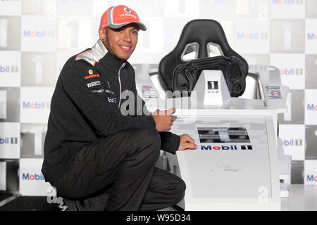 British F1 driver Lewis Hamilton del team McLaren-Mercedes pone con una F1 racing simulatore di auto durante un evento promozionale da mobile a Shanghai, C Foto Stock