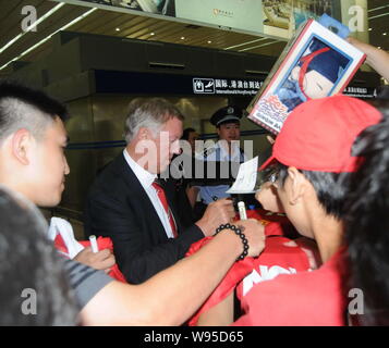 Il Manchester United manager Alex Ferguson, medio, dà il suo autografo di fan cinesi al suo arrivo con il suo team per la loro sessione off gentile soc Foto Stock