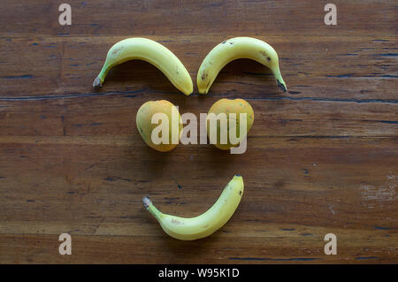 Un volto sorridente realizzata in diversi tipi di frutta su un tavolo di legno Foto Stock