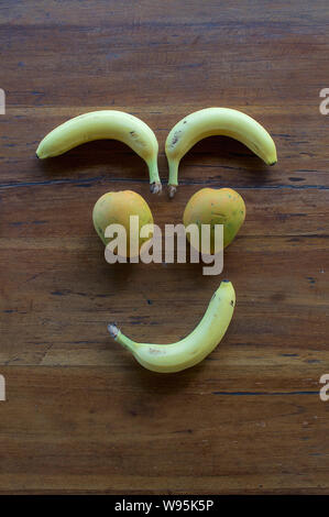 Un volto sorridente realizzata in diversi tipi di frutta su un tavolo di legno Foto Stock