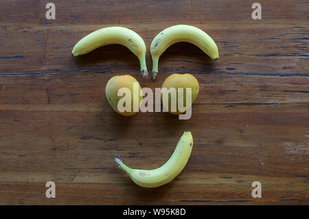 Un volto sorridente realizzata in diversi tipi di frutta su un tavolo di legno Foto Stock