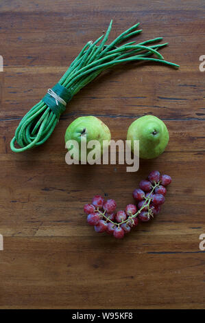Un volto sorridente realizzata in diversi tipi di frutta e verdura su una tavola di legno Foto Stock