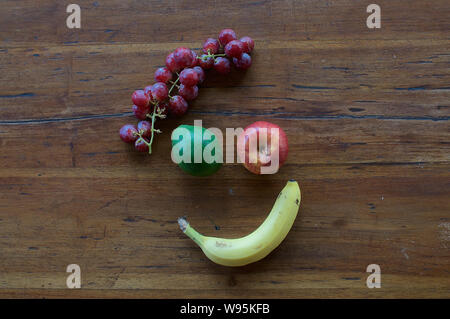 Un volto sorridente realizzata in diversi tipi di frutta su un tavolo di legno Foto Stock
