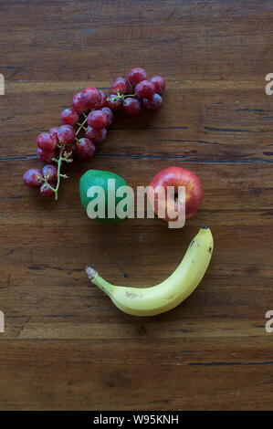 Un volto sorridente realizzata in diversi tipi di frutta su un tavolo di legno Foto Stock
