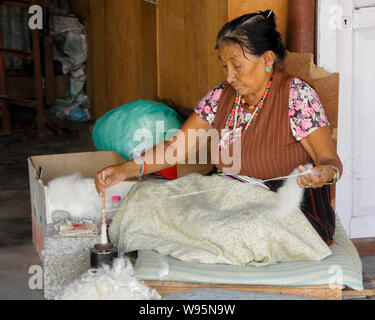 Anziano tibetano donna la filatura della lana presso un laboratorio di tappeti in Tashi-Ling comunità tibetana vicino a Pokhara, Nepal Foto Stock