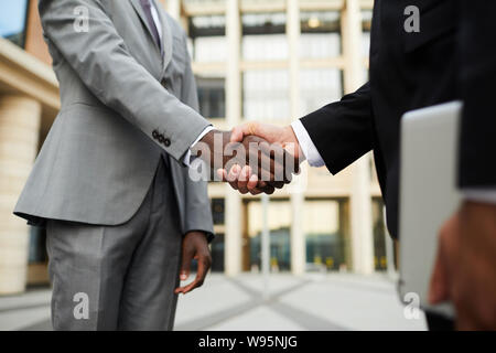 Close-up di business multietnico di persone in giacca in piedi e agitando mani essi saluto ogni altra prima riunione all'aperto Foto Stock
