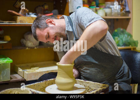 Maschio professionale potter rendendo caraffa nel laboratorio di ceramica Foto Stock