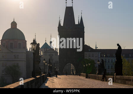 Vista Silhouette di persone godono di una bella giornata di sole sul Ponte Carlo, e sullo sfondo della torre del ponte della Città Vecchia e la chiesa di San Salvator in mattina. Foto Stock