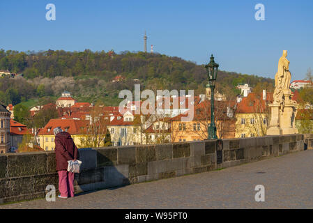 Anziano turista donna stand e guardare il fiume Moldava dal Ponte Carlo, e sullo sfondo della statua di San Francesco Borgia, edifici su Riverside . Foto Stock