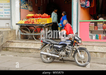 Motocicletta e frutta carrello davanti ai negozi nel Vecchio Bazar area di Pokhara, Nepal Foto Stock