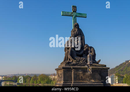 Statue di pietà o statua del Compianto di Cristo, stand su balaustre di Charles Bridge e dello sfondo del fiume Moldava e le legioni Bridge. Foto Stock