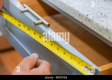 Installazione di misurazione di maniglie cassetti su mobili da cucina Foto Stock