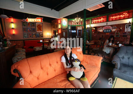 Una giovane donna seduta nel lettino arancione orologi DVD della serie TV con gli amici in un Central Perk cafe a Shanghai in Cina, 3 settembre 2012. Central Foto Stock