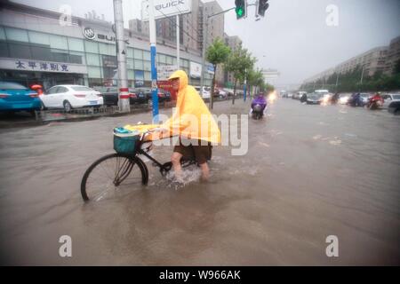 I ciclisti e i veicoli brave inondazioni su una strada in forte pioggia causata dal tifone Haikui in Cina a Shanghai, 8 agosto 2012. Il terzo ciclone tropicale in Foto Stock