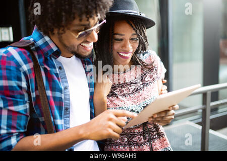 Felice coppia giovane utilizzando una tavoletta digitale insieme e sorridente. Foto Stock