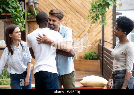 Felice diversi amici maschio abbraccio incontro al raduno amichevole Foto Stock