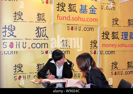 --FILE--un dipendente cinese di colloqui con un visitatore presso lo stand della Sohu.com durante una mostra a Shanghai in Cina, 19 novembre 2011. Utile netto a così Foto Stock