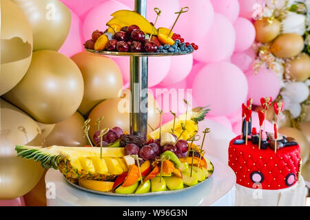 Una splendida torta decorata con rossetti e cuori per il compleanno di una giovane ragazza. Candy bar con dolci, frutta, decorazione con palloncini per weddi Foto Stock