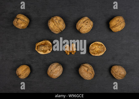 Gruppo di lotto intero di due pezzi di ripe noce marrone disposti simmetricamente flatlay sulla pietra grigia Foto Stock