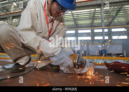 --File--un lavoratore cinese lucidi un prodotto d'acciaio in una fabbrica nella città di Nantong, est Chinas provincia dello Jiangsu, 29 luglio 2012. Chinas crescita del commercio plun Foto Stock