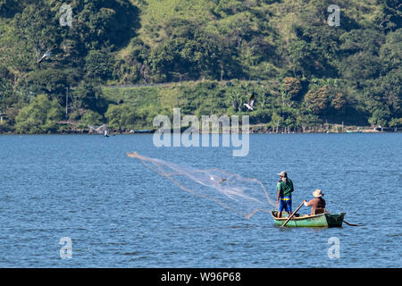 I pescatori usano un cast net presso il lago in Catemaco Catemaco, Veracruz, Messico. La tropicale lago di acqua dolce al centro della Sierra de Los Tuxtlas, è una destinazione turistica popolare e conosciuto per libera compresa scimmie, la foresta pluviale sfondo e streghe messicano noto come Brujos. Foto Stock