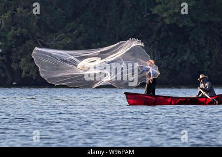 I pescatori usano un cast net presso il lago in Catemaco Catemaco, Veracruz, Messico. La tropicale lago di acqua dolce al centro della Sierra de Los Tuxtlas, è una destinazione turistica popolare e conosciuto per libera compresa scimmie, la foresta pluviale sfondo e streghe messicano noto come Brujos. Foto Stock