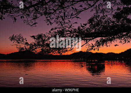 Tramonto sul lago in Catemaco Catemaco, Veracruz, Messico. La tropicale lago di acqua dolce al centro della Sierra de Los Tuxtlas, è una destinazione turistica popolare e conosciuto per libera compresa scimmie, la foresta pluviale sfondo e streghe messicano noto come Brujos. Foto Stock