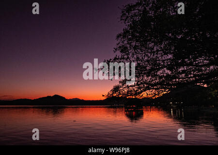 Tramonto sul lago in Catemaco Catemaco, Veracruz, Messico. La tropicale lago di acqua dolce al centro della Sierra de Los Tuxtlas, è una destinazione turistica popolare e conosciuto per libera compresa scimmie, la foresta pluviale sfondo e streghe messicano noto come Brujos. Foto Stock