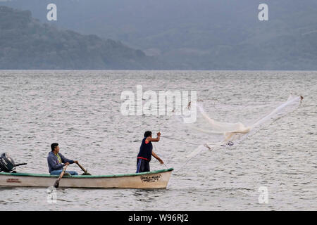 I pescatori usano un cast net presso il lago in Catemaco Catemaco, Veracruz, Messico. La tropicale lago di acqua dolce al centro della Sierra de Los Tuxtlas, è una destinazione turistica popolare e conosciuto per libera compresa scimmie, la foresta pluviale sfondo e streghe messicano noto come Brujos. Foto Stock