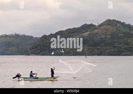 I pescatori usano un cast net presso il lago in Catemaco Catemaco, Veracruz, Messico. La tropicale lago di acqua dolce al centro della Sierra de Los Tuxtlas, è una destinazione turistica popolare e conosciuto per libera compresa scimmie, la foresta pluviale sfondo e streghe messicano noto come Brujos. Foto Stock